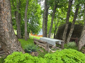 A rustic outdoor setting with a wooden bench, a metal table, and a fence.