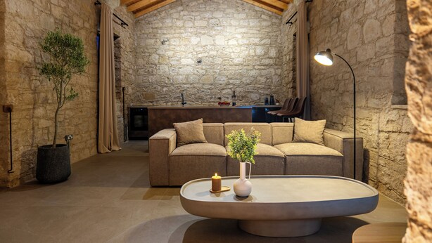 Ein gemütliches Zimmer mit Steinwand, einer Couch, einem Couchtisch und einer Lampe.