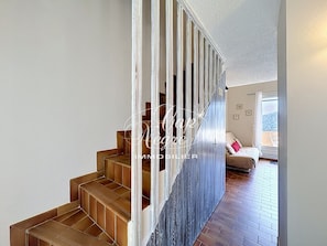 Eine Treppe mit Holzsitzen führt zu einem Zimmer mit einem Bett und einem Fenster.