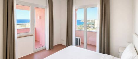 Una habitación de hotel con cama, cortinas y balcón con vistas.
