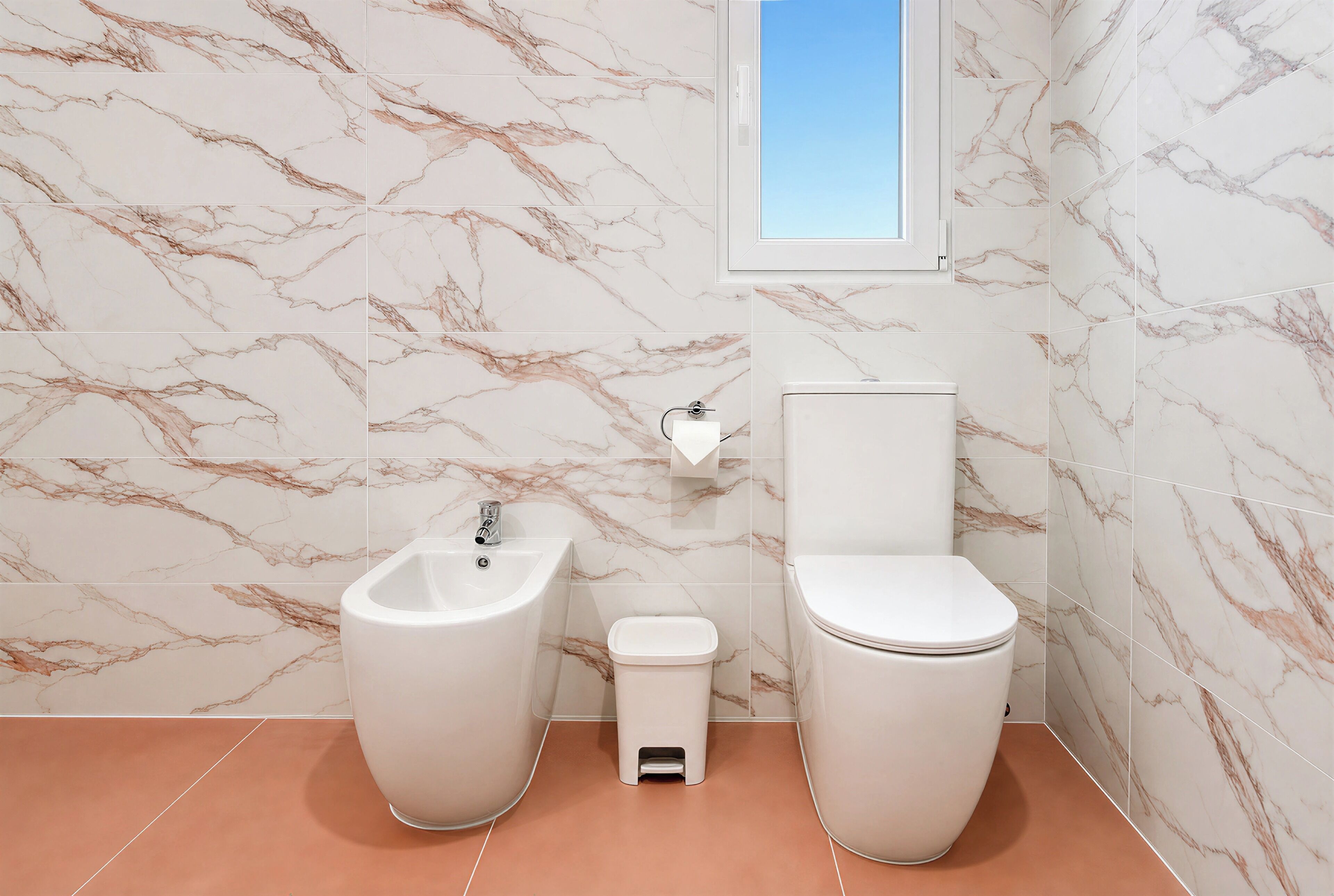 Une salle de bain équipée d’un bidet, de toilettes et d’une petite poubelle.