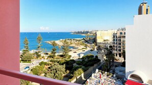 A coastal cityscape with buildings, a beach, and sailboats. - Flamingo Apartments in Vegas Resort, Malta (San Ġiljan)