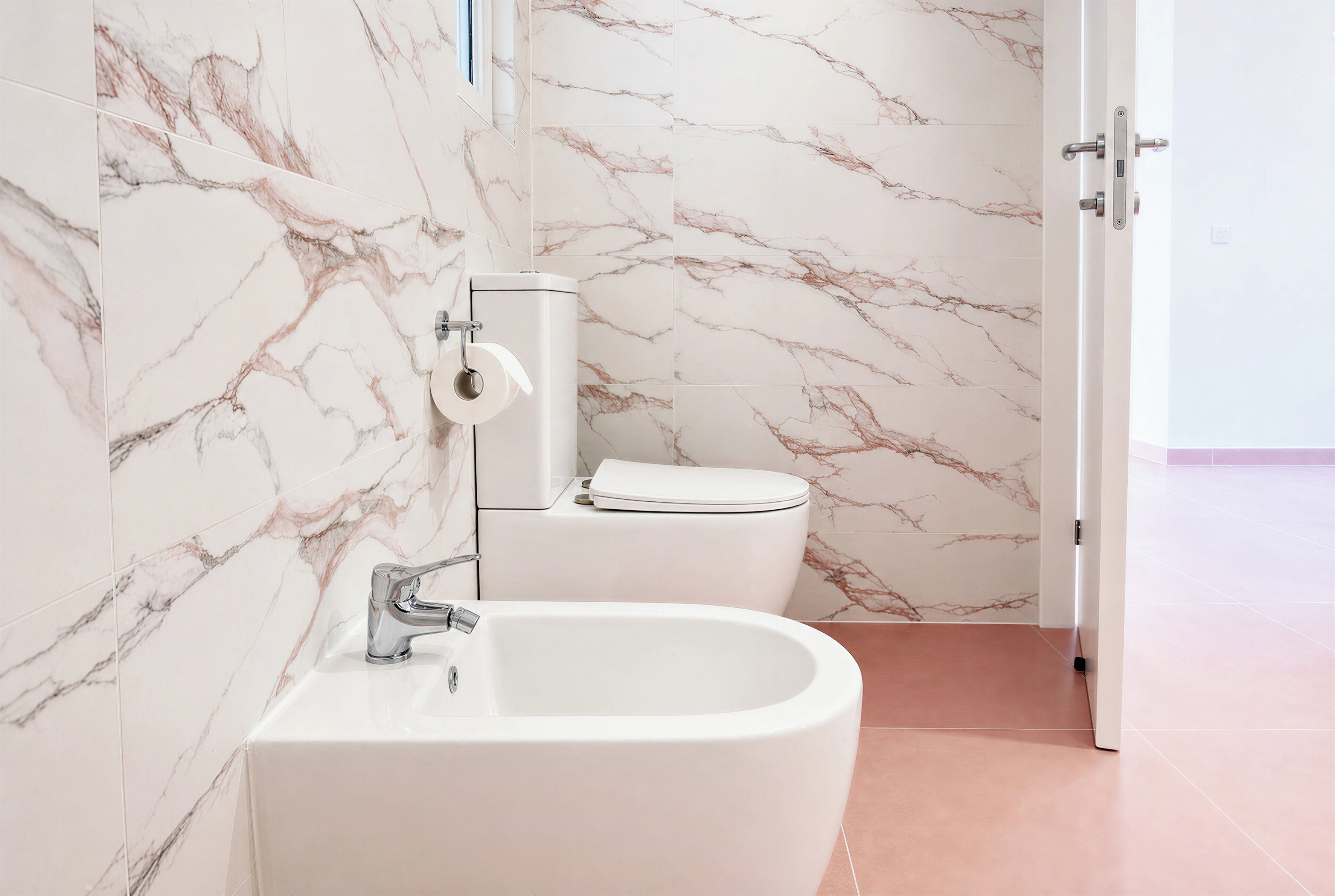 A bathroom with a marble wall, a white sink, and a toilet.