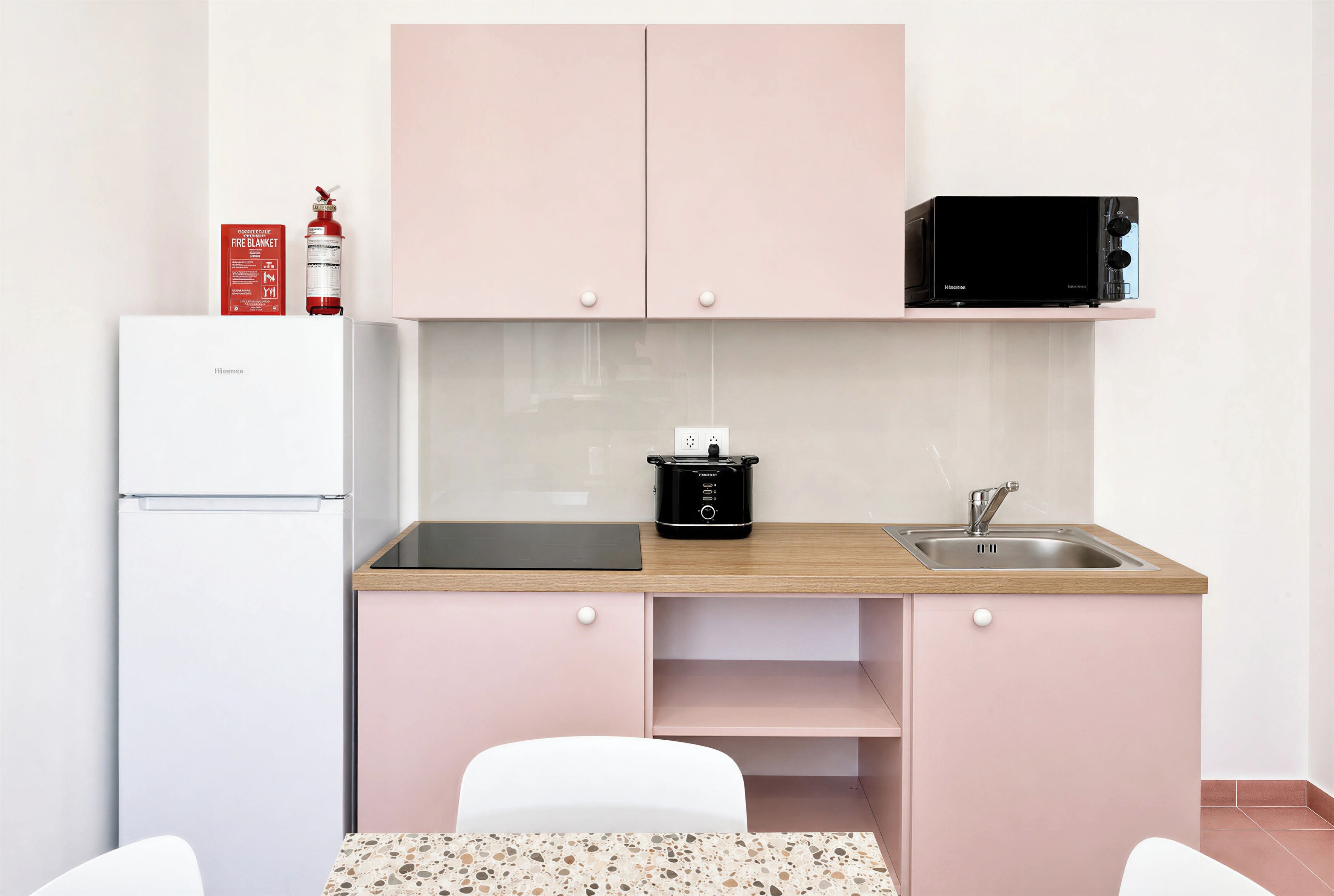 A compact kitchenette with a microwave, a stove, a sink, and a refrigerator.