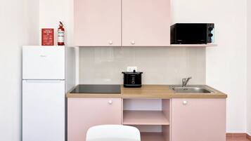 Una kitchenette compacta con microondas, estufa, fregadero y refrigerador.