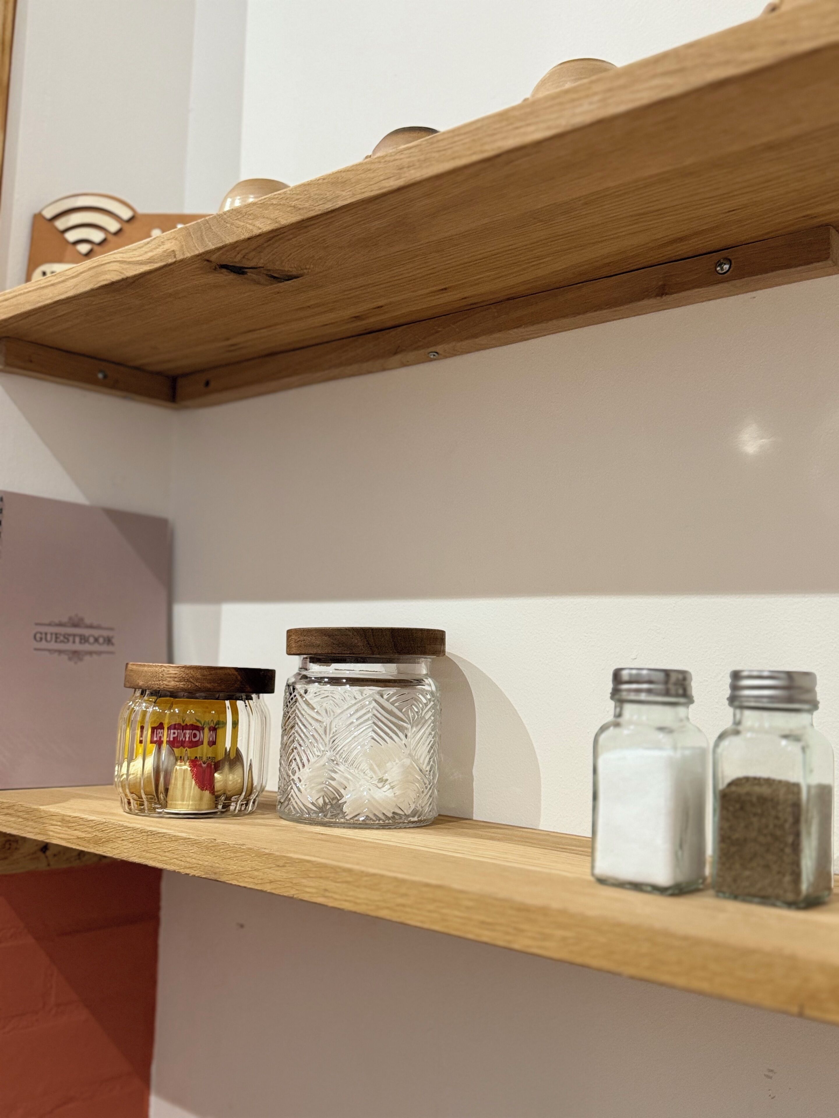 A wooden shelf with glass jars and salt shakers.