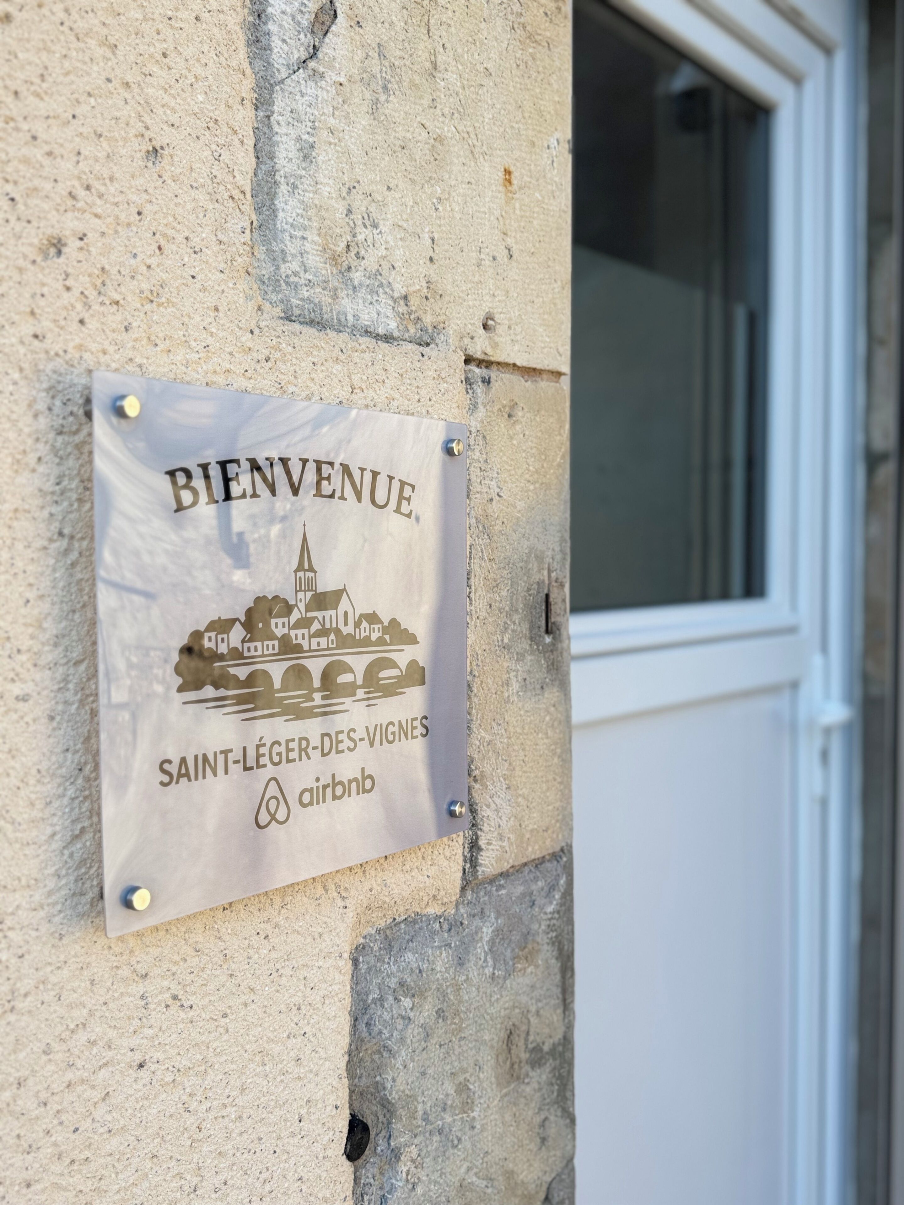Une pancarte d’accueil pour l’Airbnb de Saint-Léger-des-Vignes, fixée à un mur en pierre.