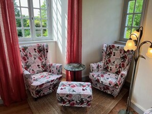 A room with two floral armchairs, a small round table, and a floor lamp. - Château de Planquery (Planquery)