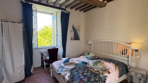 A bedroom with a bed, a chair, a desk, and a window with curtains. - Château de Planquery (Planquery)