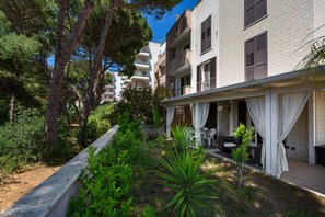 Ein Wohngebäude mit Balkon, Sitzgelegenheit im Freien und viel Grün.