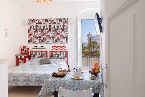 Ein Schlafzimmer mit einem Bett, einem Tisch mit Frühstücksgebäck, Wandgestaltung mit Comic-Kunst und Blick durch eine offene Tür.