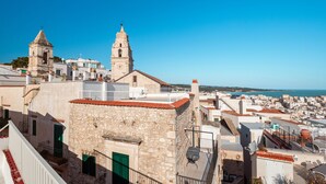 Un pueblo costero con edificios de piedra, una iglesia con dos torres y un cielo azul despejado.