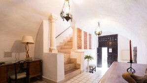 Una habitación con una escalera, un escritorio, una silla, una lámpara y una mesa con un osito de peluche.