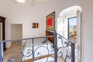 Una camera da letto con un letto, una porta che dà su un balcone e vista sul mare.