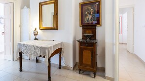Una habitación con un aparador de madera, un espejo enmarco y una mesa con mantel de encaje.