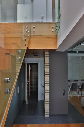 A modern interior with a staircase, a door leading to another room, and a dining area with chairs.