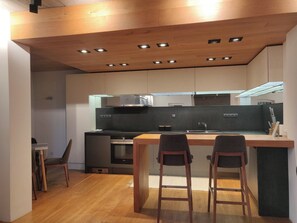 Une cuisine moderne dotée d’un îlot central, d’un four encastré et d’un éclairage intégré.