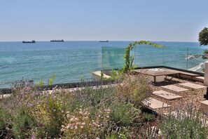 Eine Dachterrasse mit Meerblick, Sitzgelegenheiten im Freien und ein Garten mit verschiedenen Pflanzen.