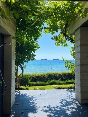 Blick durch eine Tür zu einem Balkon mit Wasserblick und Schiffen in der Ferne.
