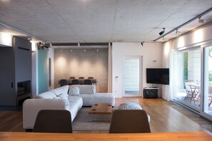 Ein modernes Wohnzimmer mit Sofa, Couchtisch, Fernseher und einer Schiebetür zu einem Außenbereich.
