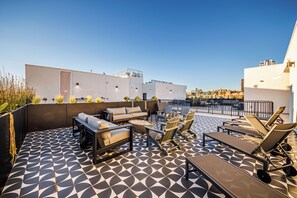 Una terraza en la azotea con mobiliario exterior, un hogar para fuego y vistas del horizonte urbano.