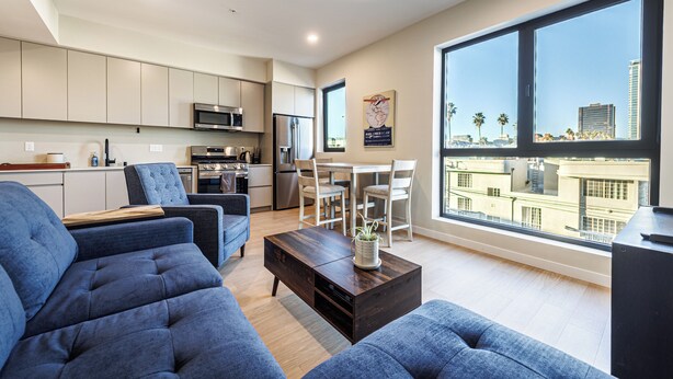 Een modern appartement met keuken, eethoek en grote ramen met uitzicht over de stad.