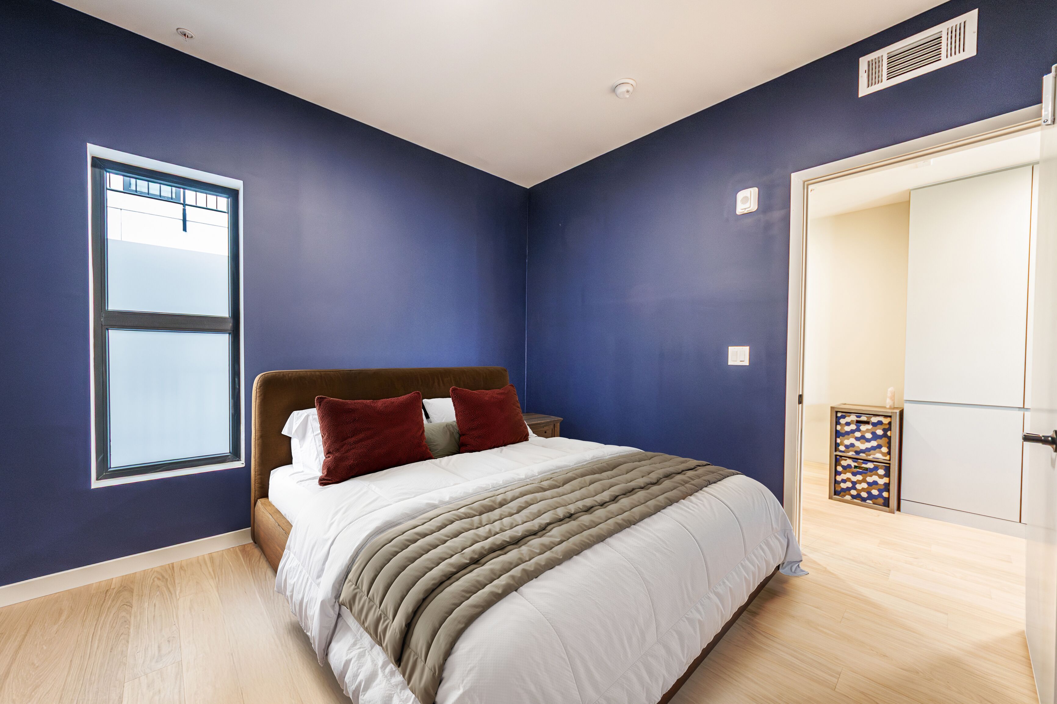 Une chambre à coucher avec un lit, une fenêtre, une porte et une étagère intégrée.