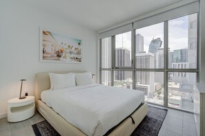 Ein modernes Hotelzimmer mit einem großen Bett, Blick auf die Stadt und einem minimalistischen Design.