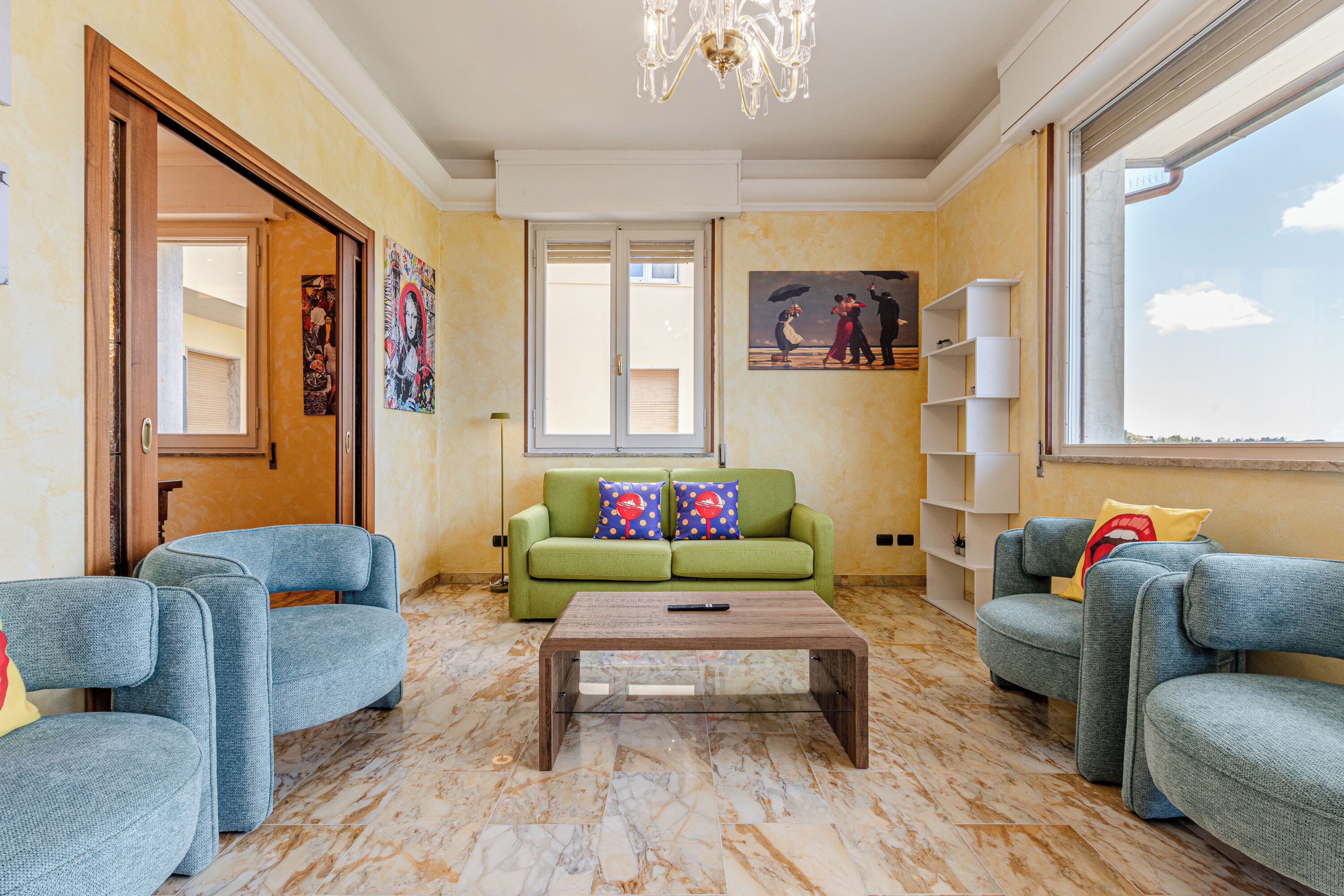 A living room with a green sofa, two blue armchairs, a wooden coffee table, and a painting on the wall.