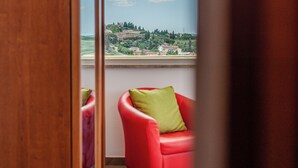 Ein Zimmer mit Blick auf eine Hügelsicht, ein roter Sessel mit grüner Sitzkissen und ein Holztürrahmen.