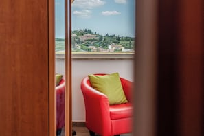 A room with a view of a hillside, a red chair with a green cushion, and a wooden door frame. - Spacious apartment a few steps from the historic center of Siena with terrace (Siena)