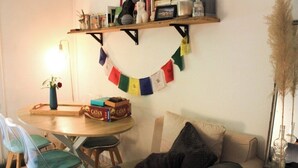 Een gezellige woonkamer met een ronde houten tafel, twee stoelen, een bank en een boekenkast met diverse spullen.