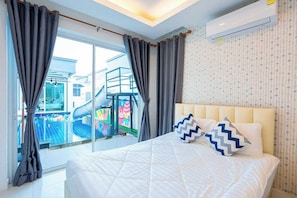 A bedroom with a bed, curtains, a window, and an air conditioning unit.