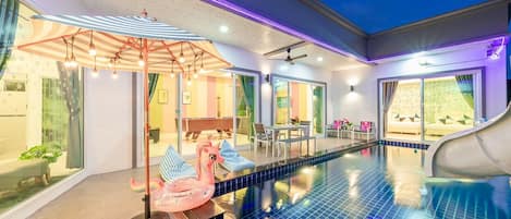Una piscina con tobogán, un ventilador de techo y una estatua de pony rosa.