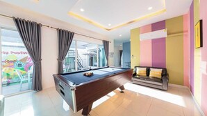 A pool table in a room with a sofa, a window with curtains, and a colorful wall. - Sunday Villa Green Shawty Pattaya (Bang Lamung)