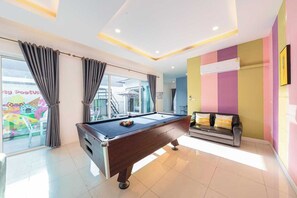 A pool table in a room with a sofa, a window with curtains, and a colorful wall. - Sunday Villa Green Shawty Pattaya (Bang Lamung)