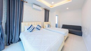A modern bedroom with a large bed, a sofa, an air conditioning unit, and a patterned curtain. - Sunday Villa Green Shawty Pattaya (Bang Lamung)