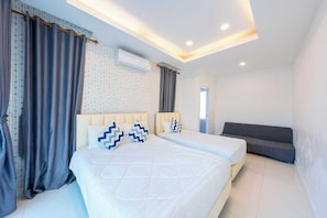 Une chambre moderne avec un grand lit, un canapé, un appareil de climatisation et un rideau à motifs.
