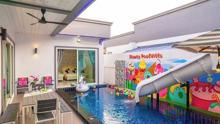 An indoor pool area with a slide, seating, and a mural.. Sunday Villa Green Shawty Pattaya