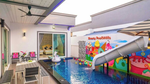 An indoor pool area with a slide, seating, and a mural.