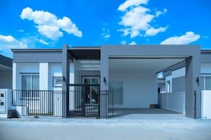 A modern building with a covered entrance, a gated driveway, and a clear sky.