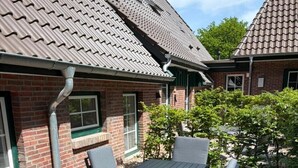 Un patio con tavolo e sedie, un muro in mattoni e una finestra.