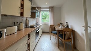 Una cocina con comedor, armarios de madera, un radiador y una ventana con cortinas.