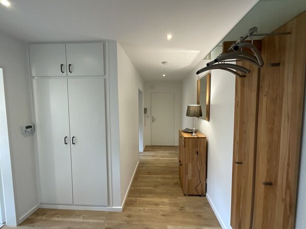 Ein Flur mit weißen Schränken, einem Holzschrank und einer Kleiderstange.