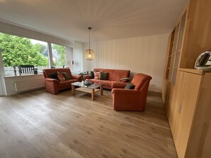 Ein Wohnzimmer mit einer Sofagarnitur, einem Couchtisch und einem Holzkabinett.