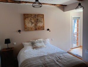 Une chambre à coucher avec un lit, une œuvre d’art représentant une carte, une table de chevet, une lampe et une fenêtre.