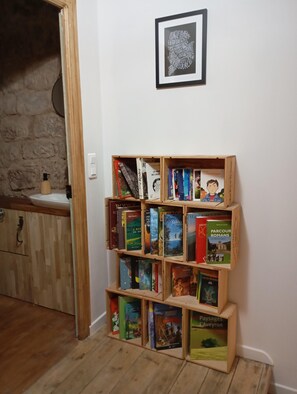 Une bibliothèque remplie de livres, un tableau représentant un nuage de mots accroché au mur et un mur de pierres en arrière-plan.