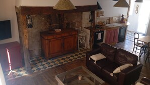 A cozy living room with a leather sofa, a glass coffee table, and a checkered floor. - Gite Le Mansois (Marcillac-Vallon)
