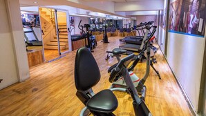 A gym with cardio machines, a staircase, and a wooden floor. - Hotel Tronador (Mar del Plata)