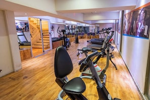 A gym with cardio machines, a staircase, and a wooden floor. - Hotel Tronador (Mar del Plata)